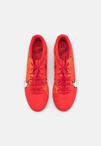 Červené fotbalové kopačky s texturovaným vzorem, černými akcenty a logem v podobě swoosh. Obsahují zavazování na šňůrky a polstrovaný vnitřek pro pohodlí.