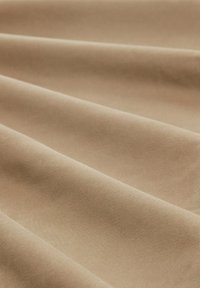 Tissu beige avec une texture lisse et un léger éclat, présentant des plis doux qui créent des vagues subtiles. Idéal pour diverses applications.