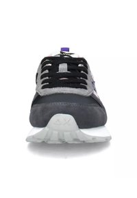 Sneaker nera e grigia con tomaia in suede e tessuto, lacci a contrasto, suola bianca e un accento viola sulla linguetta.