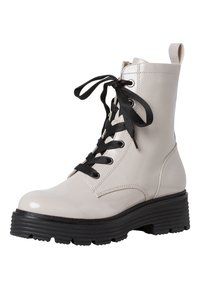 Bottines en cuir beige avec une finition brillante, lacées de noir, et une semelle en caoutchouc noir épaisse avec une texture striée.