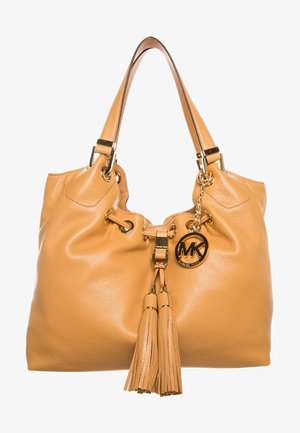 Sac à main Michael Kors en cuir couleur tan avec doubles bandoulières, fermeture par cordon à pompon, et un charm rond avec logo doré attaché.