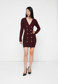 Abito in maglia bordeaux con scollatura a V profonda, maniche lunghe, motivo testurizzato, design doppiopetto e dettagli con bottoni dorati.
