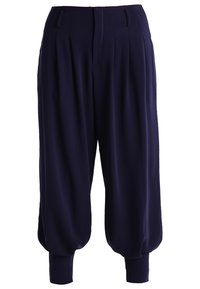 Námořnické modré kalhoty ve stylu harem vyrobené z měkké látky, s plisováním, bočními kapsami a žebrovanými manžetami u kotníků.