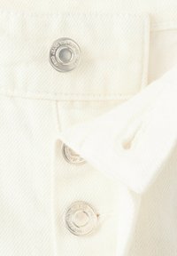 Nahaufnahme eines weißen strukturierten Stoffs mit drei glänzenden silbernen Druckknöpfen, die vertikal angeordnet sind, und einem umgeschlagenen Stoffrand.