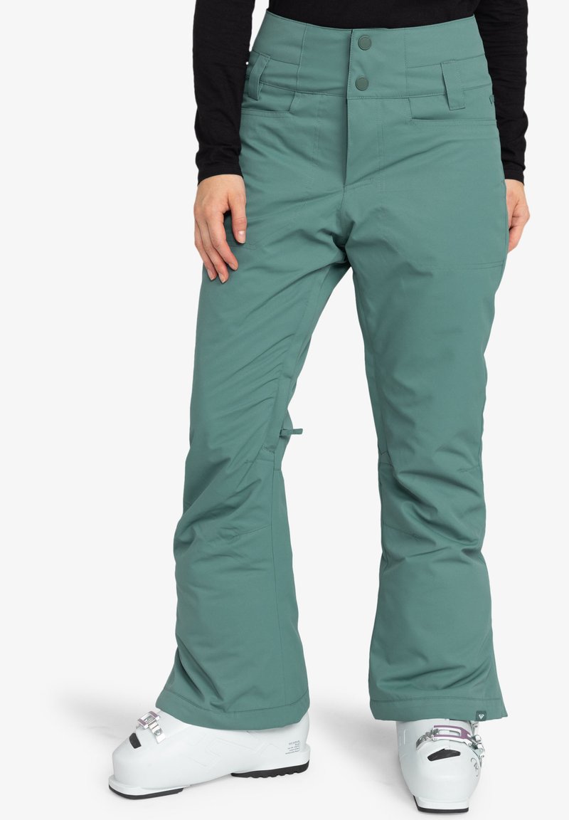 Groene sneeuwbroek met een hoge taille, twee knopen aan de voorkant, meerdere zakken en een ontspannen pasvorm. Bevat versterkte naden en een zachte stof.