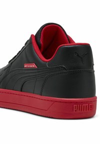 Sorte lædersneakers med røde accenter, udstyret med gummisål, teksturerede paneler og en logoetiket på siden og hælen.
