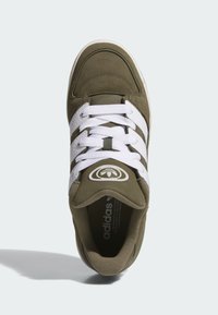 Green suede sneaker with white leather stripes, round toe, and white laces; features logo on tongue and textured sole.
