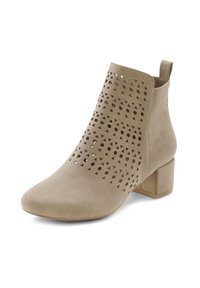Bottines beige avec découpes géométriques, petit talon bloc, texture en peau de suede lisse et bandoulière pour un enfilage facile. Bout arrondi.