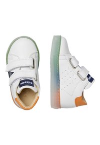 Baskets en cuir blanc avec deux bandes Velcro, accents verts et oranges, côtés perforés et une semelle en caoutchouc translucide avec un dégradé.