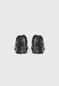 Schwarze Sportschuhe mit Obermaterial aus Mesh, strukturierten Sohlen und gepolsterten Kragen. Verfügt über ein schlankes Design und ein Schnürsystem.