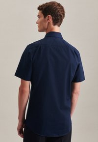 Camicia blu navy a maniche corte con yoke posteriore, colletto classico e orlo dritto. Realizzata in tessuto leggero e liscio senza motivi visibili.