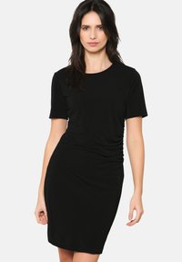 Juoda prigludusi t-shirt suknelė trumpomis rankovėmis, apvaliu iškirpimu ir susiraukšlėjimu šone, pagaminta iš minkštos, lygaus audinio.