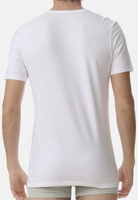 Vit bomull t-shirt med rund halsringning och korta ärmar, med en slät textur och rak fåll. Minimalistisk design.