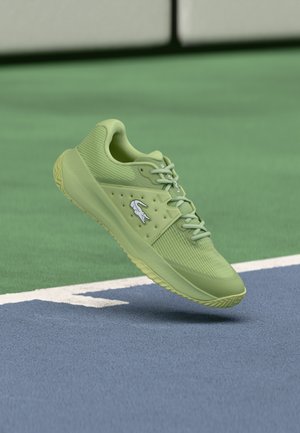 Chaussure de sport vert clair avec une tige texturée, un col rembourré et une semelle extérieure en caoutchouc, présentant un logo blanc et un design à lacets.