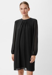Czarna sukienka z długim rękawem, wykonana z przezroczystej tkaniny, z okrągłym dekoltem, plisowanym przodem oraz elastycznymi mankietami. Długość zakończenia powyżej kolana.
