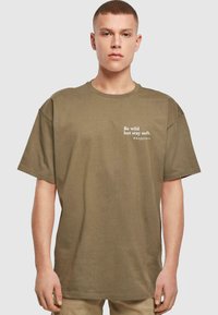 Olivenfarvet T-shirt lavet af ribbet stof med rund halsudskæring og et slogan trykt i hvidt på venstre side. Casual pasform.