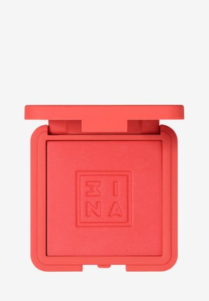 Ljust korallröd rouge i en fyrkantig, texturerad förpackning med matt yta. Locket är i en matchande stark nyans med en subtil logotyp präglad på toppen.