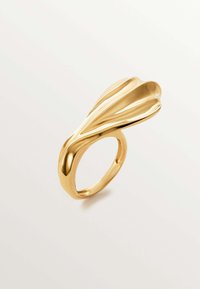 Anillo de oro con un diseño ancho y curvado, con líneas fluidas y una superficie texturizada. La banda es lisa y pulida.