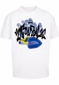 Hvid bomulds t-shirt med et farverigt grafisk design, der har tekst i graffitistil og en blå accent, sat mod en sløret blå baggrund.