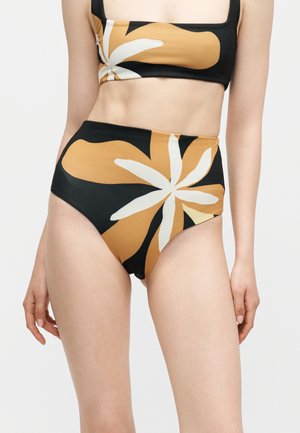 Kobieta w bikini z wysokim stanem z dużymi pomarańczowymi i białymi kwiatowymi wzorami na czarnym tle.