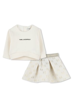 Witte katoenen sweatshirt met zwarte "KARL LAGERFELD" opdruk, gecombineerd met een witte rok met gouden geometrische patronen en een grijze tailleband.