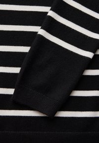 Maglione a righe bianche e nere, caratterizzato da una consistenza morbida a maglia, con righe alternanti larghe e strette, e dettagli a coste sui polsi.
