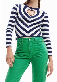 Pasiasty granatowy i biały krótkowłosy sweter z sercowym wycięciem; zestawiony z jasnoczonymi, wysoko-wyniesionymi spodniami z delikatnym logo na kieszeni.