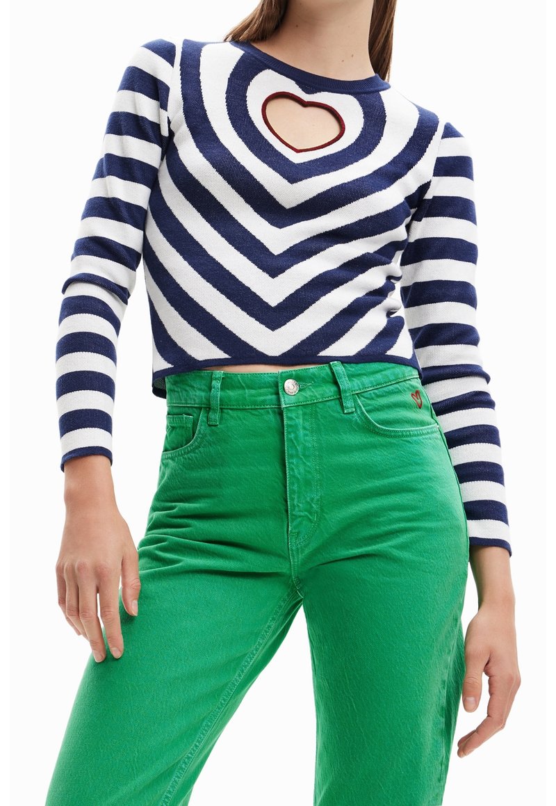 Pasiasty granatowy i biały krótkowłosy sweter z sercowym wycięciem; zestawiony z jasnoczonymi, wysoko-wyniesionymi spodniami z delikatnym logo na kieszeni.