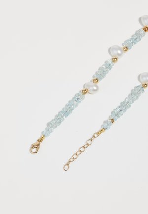 Bracelet en perles comprenant des cristaux bleu clair, des perles blanches et des accents dorés ; comprend un fermoir en homard et une chaîne ajustable.