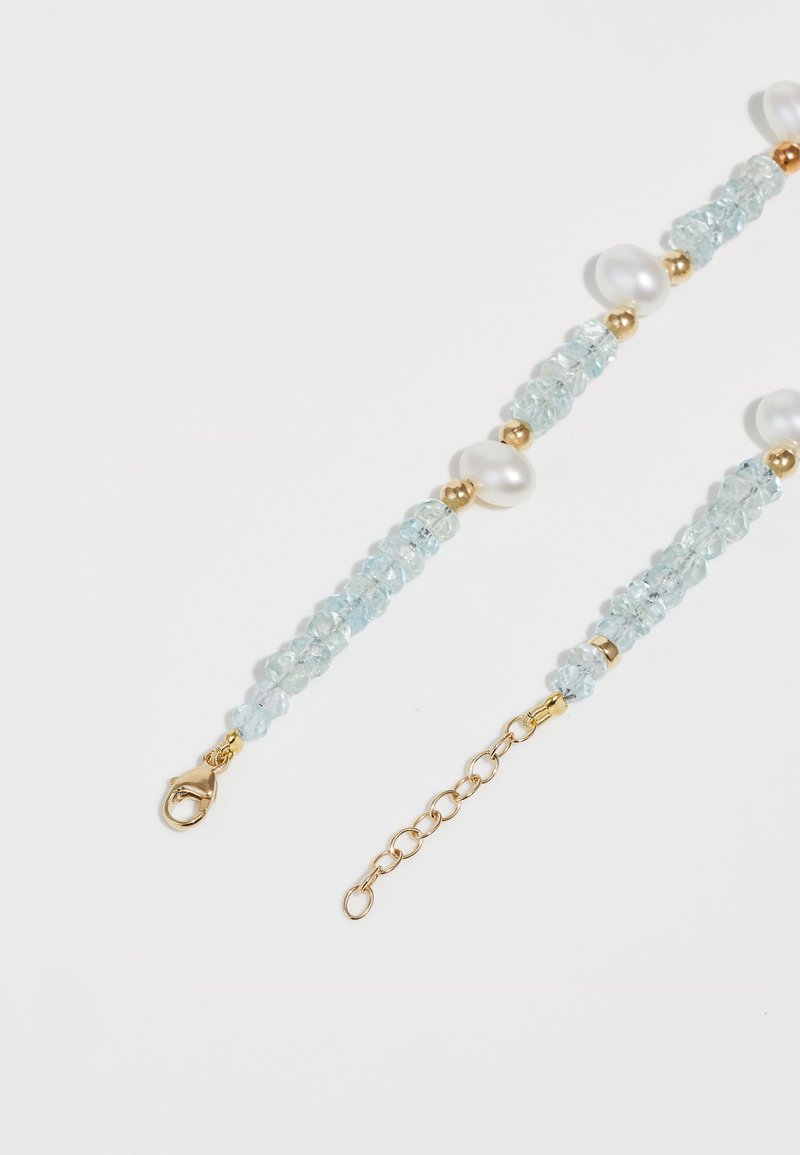 Bracelete de contas com cristais azul-claro, pérolas brancas e detalhes em ouro; inclui um fecho de lagosta e corrente ajustável.