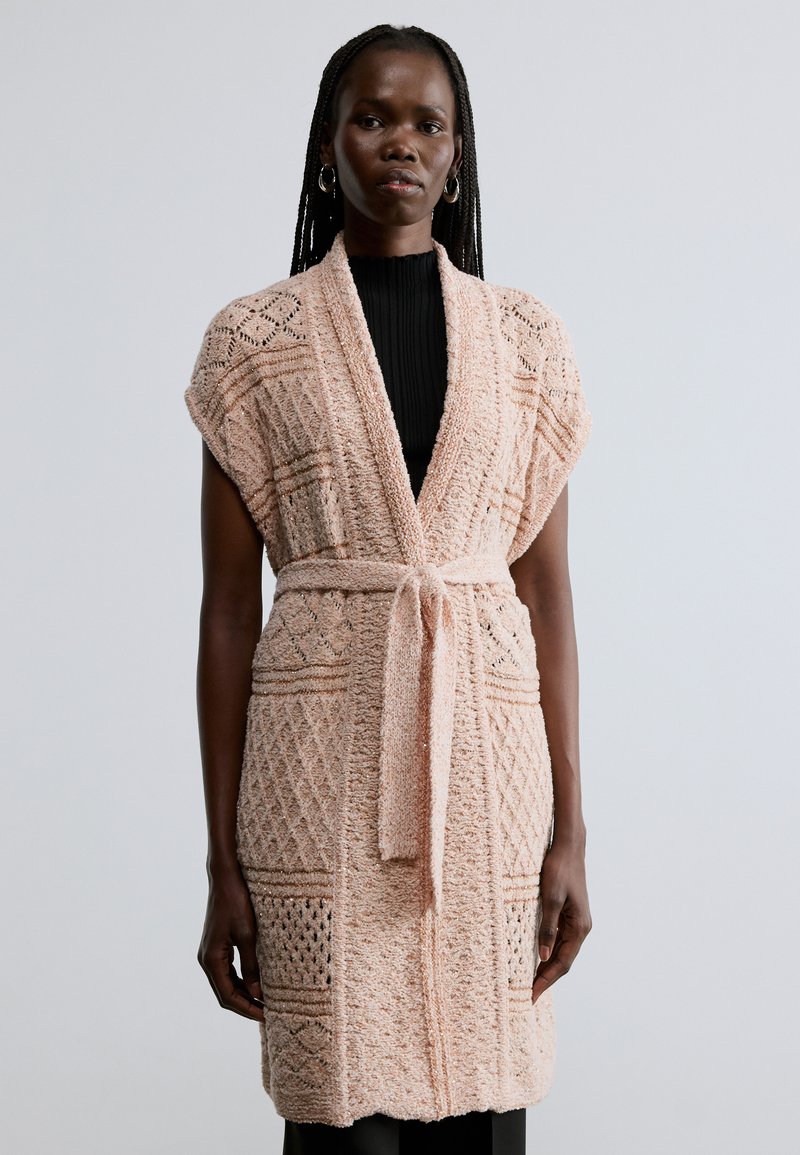 Πλεκτή ζακέτα σε απαλό ροζ με υφασμένο σχέδιο και ανοιχτό εμπρός μέρος, διακοσμημένη με ζώνη δεμένη στη μέση και κοντά μανίκια.