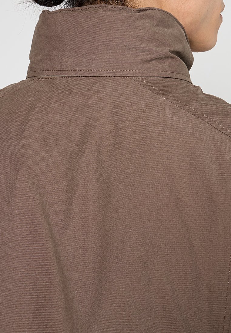 Giacca outdoor marrone con colletto alto, realizzata in tessuto testurizzato. Cuciture visibili e un design pulito e minimalista.