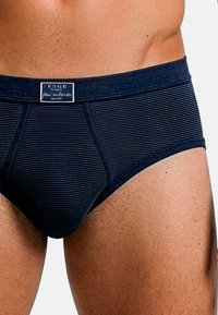 Slip a righe blu navy con una morbida fascia elastica in vita e una patch con logo. Il tessuto appare liscio, con una vestibilità aderente.