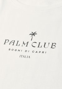 White fabric with black text reading "PALM CLUB" under a palm tree icon, and below in smaller text "SOGNI DI CAPRI ITALIA."