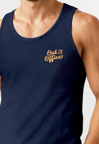 Navy tank top made of smooth fabric featuring an orange "Out of Office" graphic on the left chest area and wide shoulder straps.