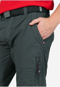 Graue strukturierte Hose mit einer Reißverschluss-Tasche an der Seite, einem dezenten Diamantmuster und einem schwarzen Gürtel mit einer silbernen Schnalle.
