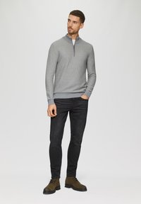Grijze quarter-zip trui met een gestructureerd patroon, gecombineerd met zwarte slim-fit jeans en bruine veterschoenen op een effen achtergrond.