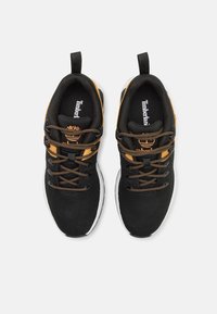 Baskets en maille noires avec des accents et des lacets orange, dotées d'une semelle blanche, d'un bout rond et d'un logo Timberland sur la languette.