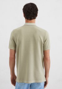 Korte mouwen polo shirt in lichtgroen, gemaakt van zachte stof, met een klassieke kraag en een rechte zoom met zijsplitten.
