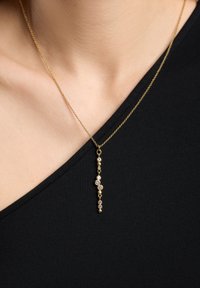 Gul vedhæng halskæde med en delikat kæde og et vertikalt dråbe-design, fremhævet af runde, glitrende sten.
