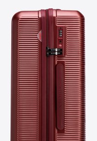 Hartschalenkoffer in metallicrosafarben. Verfügt über eine gerippte Struktur, doppelte Reißverschlüsse, ein Zahlenschloss und ein Markenlogo-Detail.