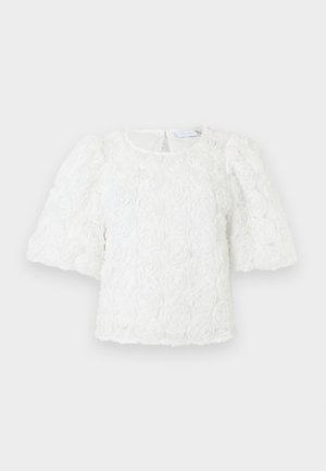 Hvid bluse med strukturerede blomsterprint, pufærmer i mellemlang længde, rund halsudskæring og lukning med knapper bagpå.