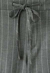 Pantalon en tissu gris avec des fines rayures blanches verticales et un cordon de serrage noué à la taille.