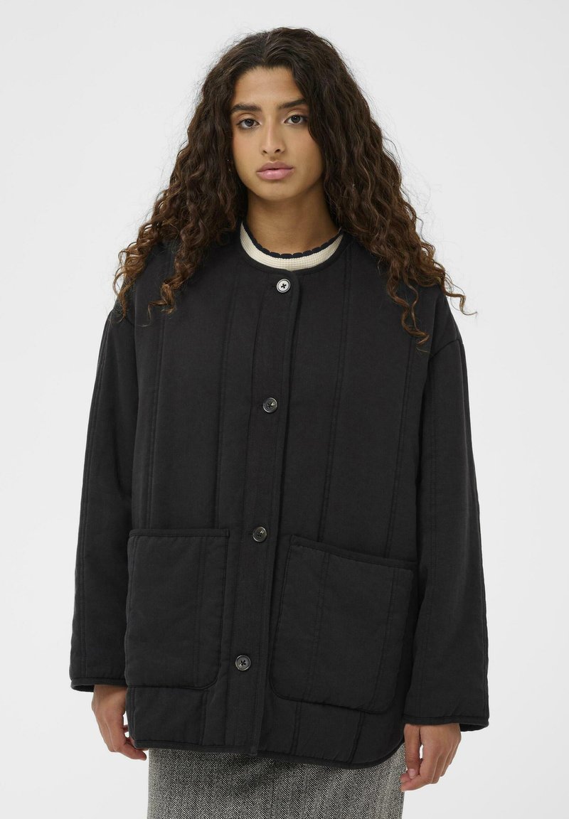 Črna prešita jakna z visokim ovratnikom, sprednjimi žepi in zapiranjem na gumbe. Tkanina ima teksturo z vertikalnimi šivi.