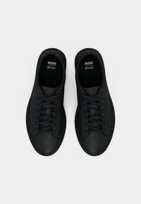 Ζευγάρι μαύρα αθλητικά παπούτσια με κορδόνια, με λογότυπα BOSS και Ortholite στις εσωτερικές σόλες, φόντο λευκό, φωτογραφία από ψηλά.