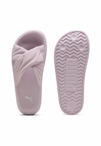 Sandales à glissière roses avec un dessus texturé présentant des éléments de design croisés, une semelle plate avec un motif en zigzag et le logo "PUMA" sur la base.