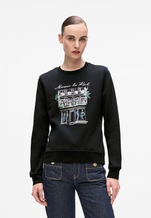 Black sweatshirt with a round neckline, featuring a graphic design of a storefront with sketches in blue and green. Soft fabric, fitted style.