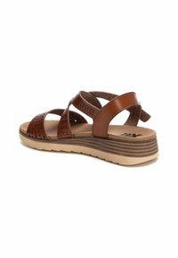 Sandalias de cuero marrón con tiras cruzadas, diseño perforado, plantilla acolchada y suela de cuña estratificada con rayas horizontales.