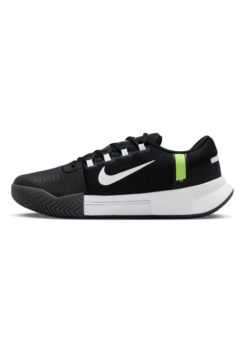 Scarpa sportiva nera con parte superiore in mesh testurizzato, logo Nike bianco e accenti verdi. Presenta una suola in gomma con un motivo di battistrada a zigzag.