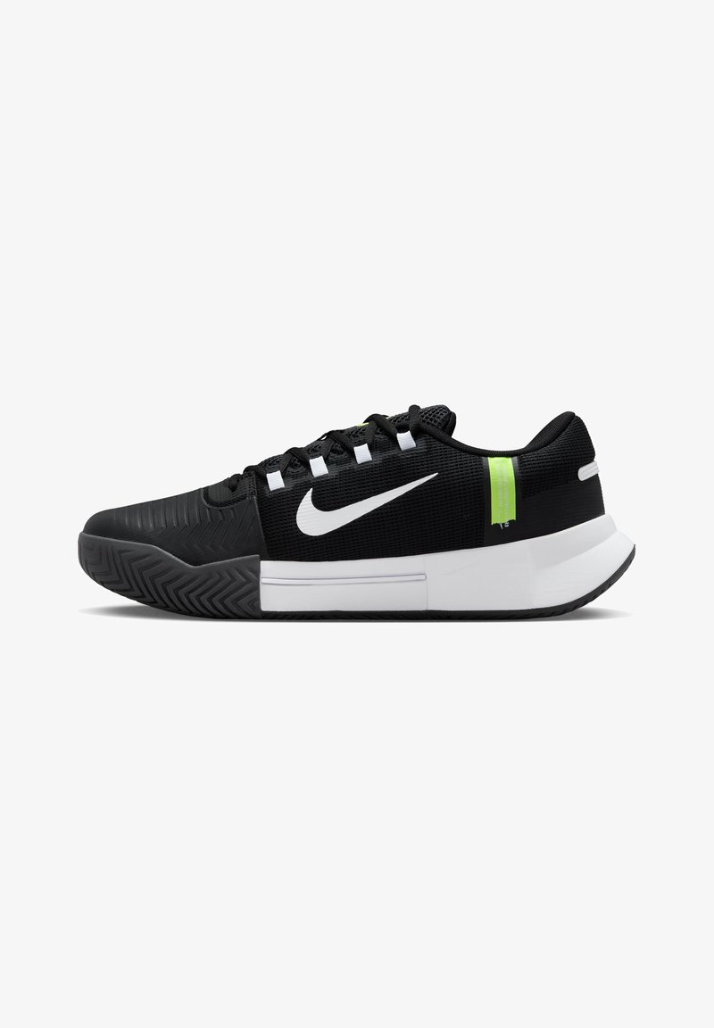 Schwarzer Sportschuh mit strukturiertem Mesh-Obermaterial, weißem Nike-Swoosh und grünen Akzenten. Verfügt über eine Gummisohle mit Zickzack-Profil.
